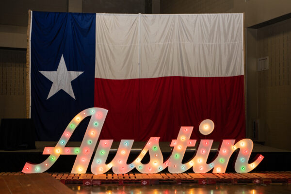 large Texas Flag hanging behind a stage with a large marquee sign that says Austin